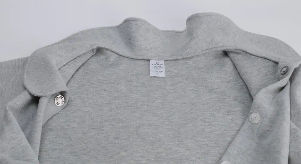 Caregiver assisting elderly woman dressing using open-back adaptive top