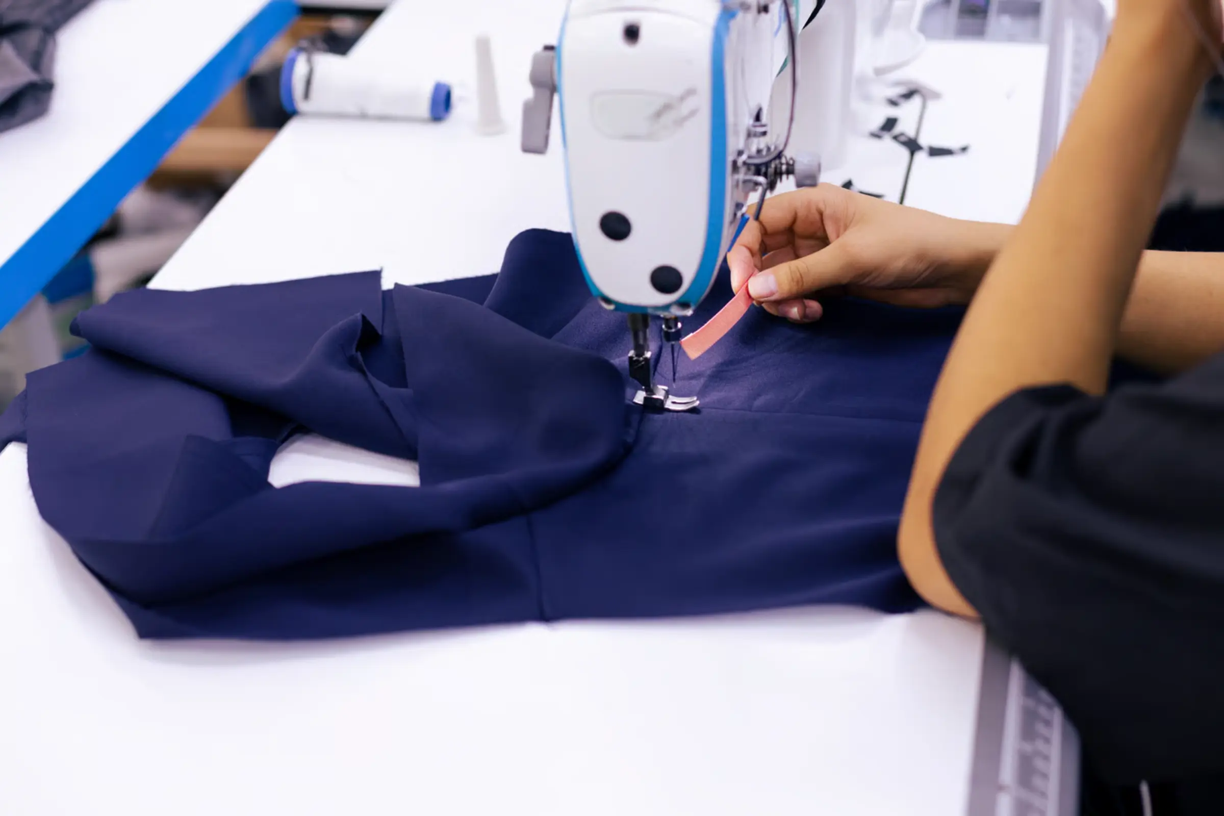 Sewing technician constructing a magnetic-closure adaptive garment on an industrial line